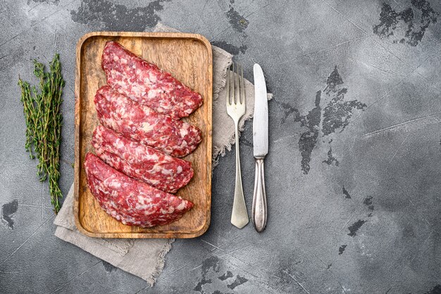 Set di cotolette di hamburger di manzo di carne macinata cruda, su sfondo di tavolo in pietra grigia, vista dall'alto piatta, con spazio di copia per il testo