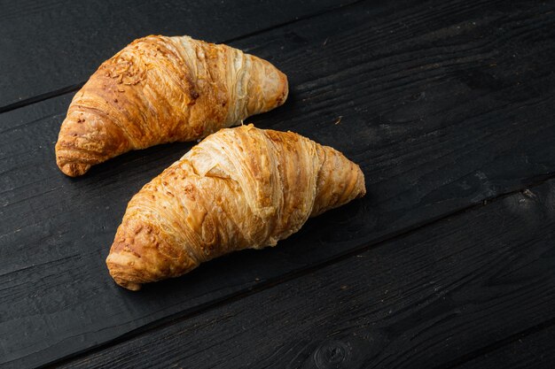 Set di croissant freschi croccanti, sul fondo della tavola in legno nero