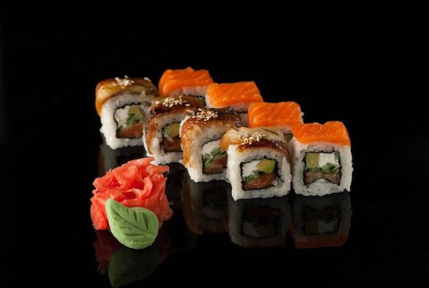 Set di cubetti di sushi con wasabi su sfondo nero con riflesso