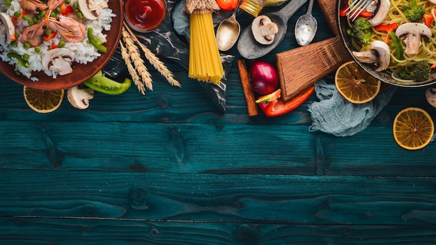 Set di cucina asiatica Risotto con spaghetti di gamberi con verdure Frutti di mare Su uno sfondo di struttura in legno Vista dall'alto Spazio libero