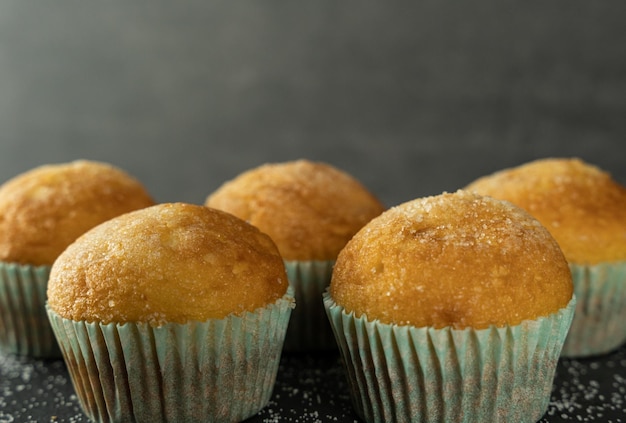 Set di deliziosi cupcakes appena sfornati con zucchero in cima su uno sfondo