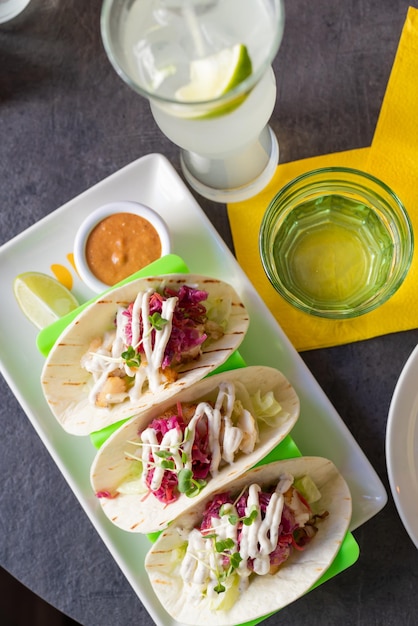 Set di deliziosi tacos su salsa di plastica e limonata vista dall'alto del caffè messicano