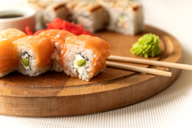 Set di delizioso rotolo di sushi di salmone philadelphia servito con wasabi e bacchette su tavola di legno