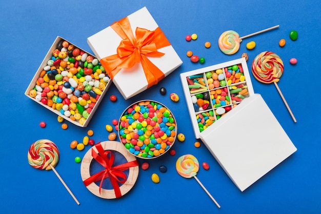 Set di diverse caramelle dolci in una scatola di carta con un nastro di raso su uno sfondo colorato concetto di vacanza