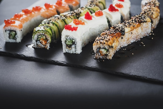 Set di diversi rotoli di sushi su sfondo nero