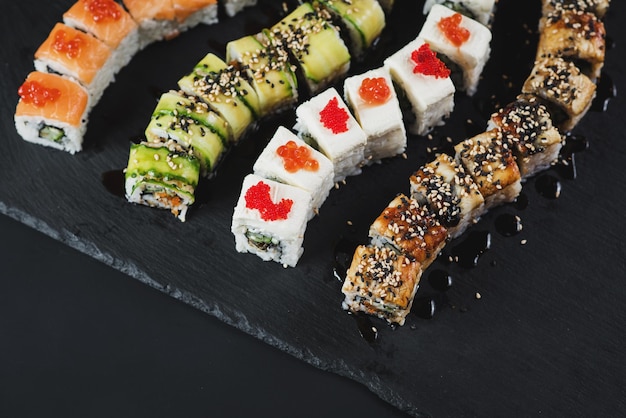 Set di diversi rotoli di sushi su sfondo nero