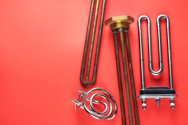 Set di diversi tipi Elementi riscaldanti elettrici tubolari in acciaio per lavatrici riscaldamento ad acqua bollente isolato su sfondo rosso