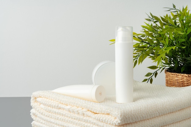 Set di flaconi per la cosmetica vuoti e asciugamani su sfondo grigio
