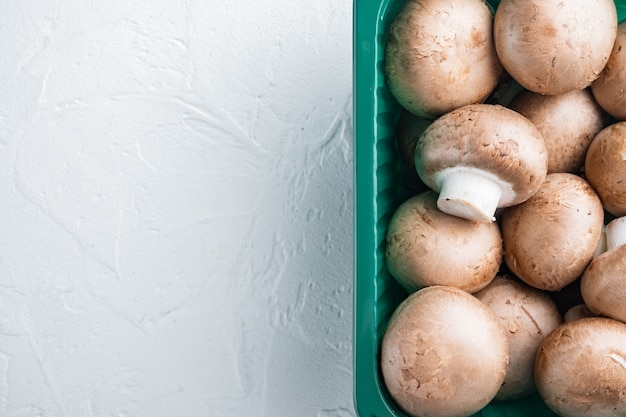 Set di funghi champignon marroni, su sfondo bianco, in confezione di plastica, vista dall'alto laici piatta, con spazio per il testo copyspace