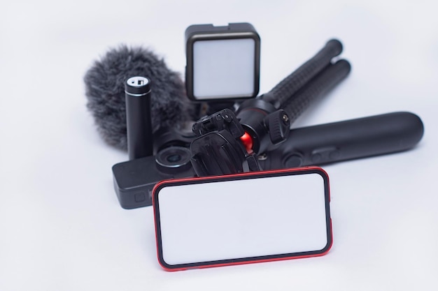 Set di gadget per blog Mockup di smartphone con schermo bianco con power bank per treppiede con action camera e stabilizzatore con microfono su sfondo bianco