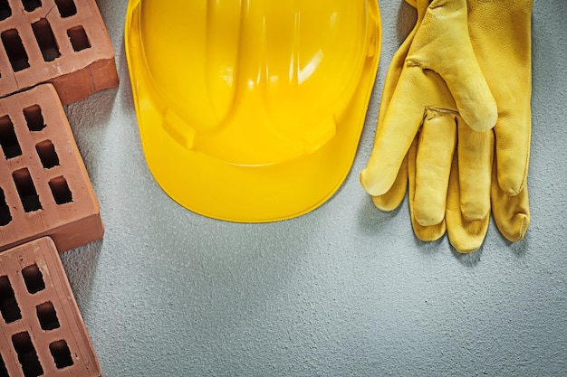 Set di guanti di sicurezza per elmetto protettivo in mattoni rossi sul concetto di costruzione di fondo in cemento