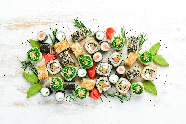 Set di gustosi rotoli di sushi e maki su sfondo bianco di legno Cibo giapponese Vista dall'alto Spazio libero per il testo