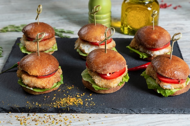 Set di hamburger di pesce a bordo nero sulla tavola di legno