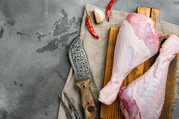 Set di ingredienti per cosce di tacchino crudo, su tagliere di legno, su sfondo di tavolo in pietra grigia, vista dall'alto piatto, con spazio per la copia del testo