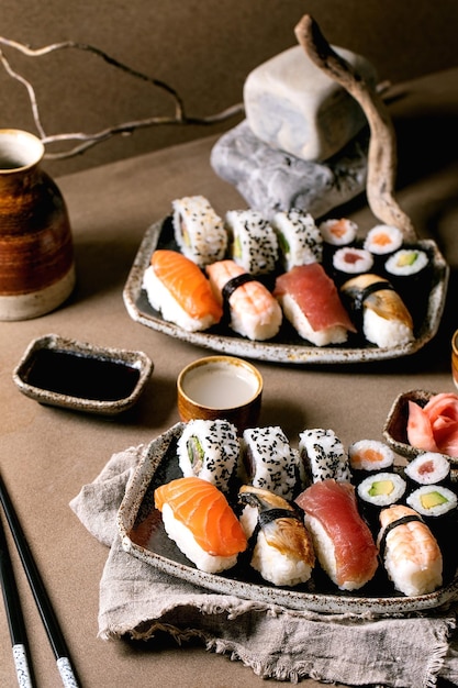 Set di involtini di sushi per due Piatto tradizionale giapponese Sushi e involtini con salmone fresco, anguilla di tonno e gamberi su riso Servire su piatti con salsa di soia e sake su tavola marrone Cena in stile giapponese