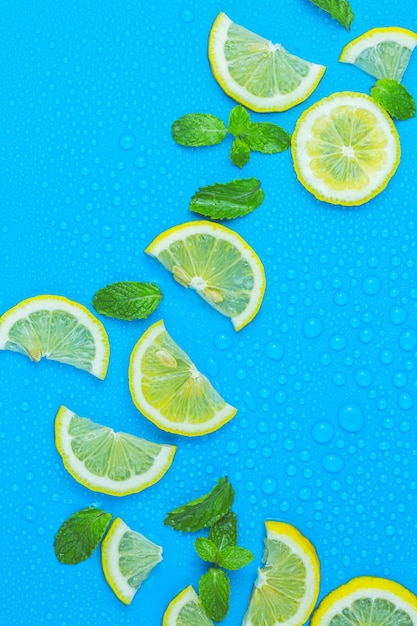 Set di limone con cubetti di ghiaccio e foglie di menta su sfondo blu Diverse fette di limone vista dall'alto