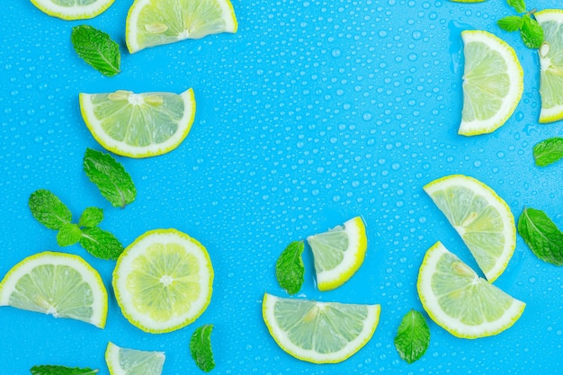Set di limone con cubetti di ghiaccio e foglie di menta su sfondo blu Diverse fette di limone vista dall'alto