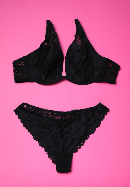 Set di lingerie in pizzo nero su sfondo rosa piatto