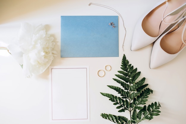 Set di lusso di partecipazioni di nozze, fedi nuziali, accessori eleganti della sposa su uno sfondo bianco.