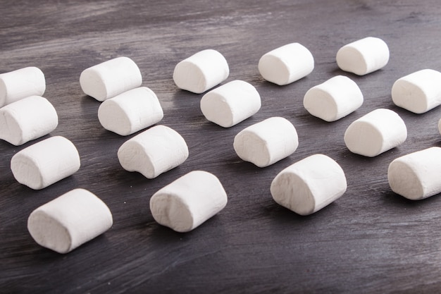 Set di marshmallow su fondo di legno nero. motivo geometrico.