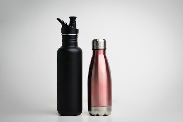 Set di moderne bottiglie thermos in diversi colori su sfondo bianco Closeup di bottiglie di acciaio termo eco riutilizzabili per qualsiasi liquido