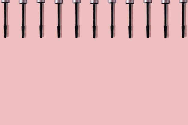 Set di molti pennelli per mascara neri con ombre nitide isolate su sfondo rosa con spazio per la copia Motivo a sbavature del prodotto di bellezza xD