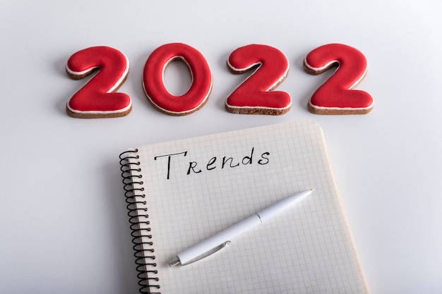 Set di numeri 2022 e taccuino con iscrizione TRENDS su sfondo bianco. Le tendenze della moda nel nuovo anno.