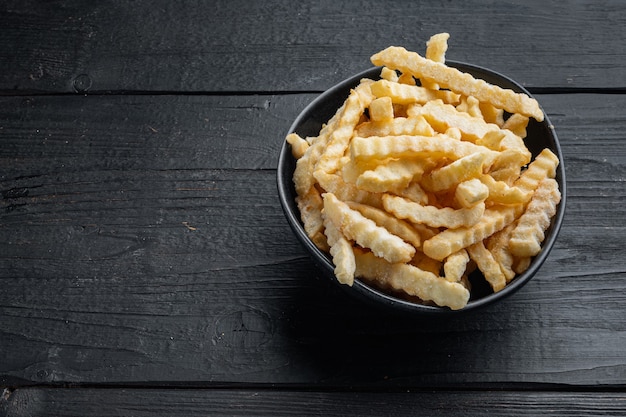 Set di patate a fette di patatine fritte da forno congelate, su sfondo di tavolo in legno nero, con copyspace e spazio per il testo