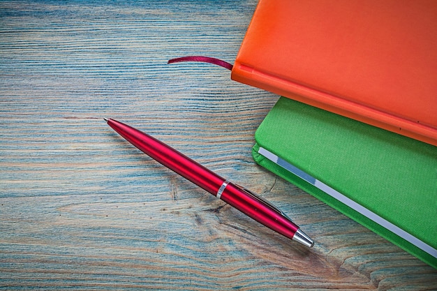 Set di penna a sfera con blocco note chiuso su tavola di legno vintage concetto di ufficio