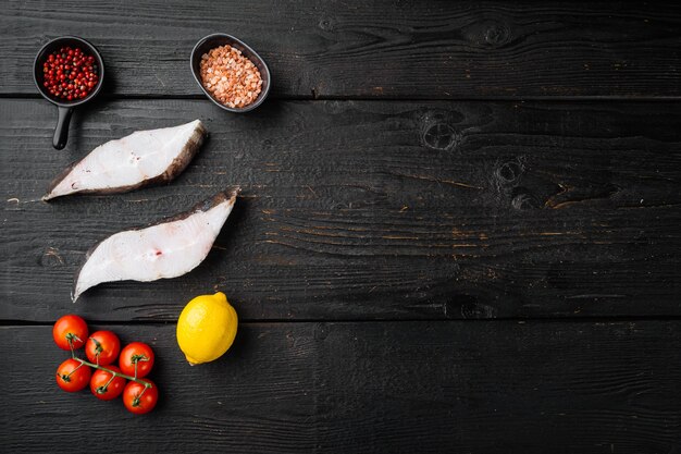 Set di pesce halibut affettato, con ingredienti ed erbe di rosmarino, su sfondo tavolo in legno nero, vista dall'alto piatta, con copia spazio per il testo