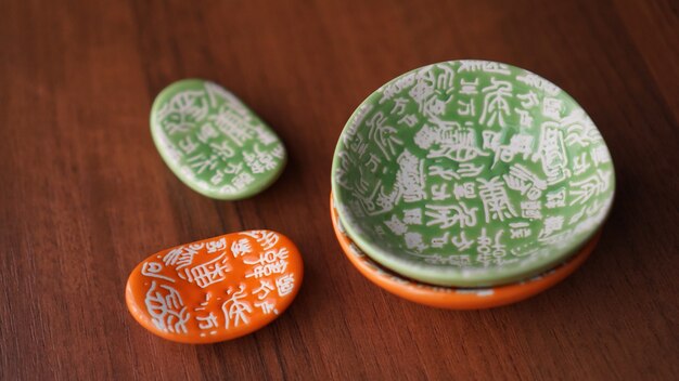 Set di piatti vuoti in ceramica verde e arancione e supporti per bastoncini di sushi su fondo di legno