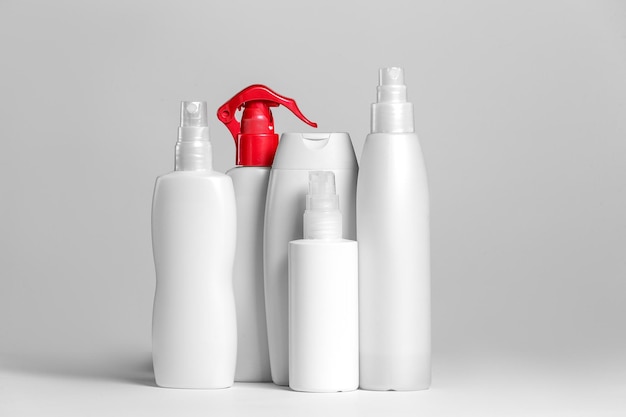Set di prodotti cosmetici in contenitori bianchi e grigi su sfondo chiaro