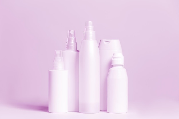 Set di prodotti cosmetici in contenitori rosa e grigi su sfondo chiaro.