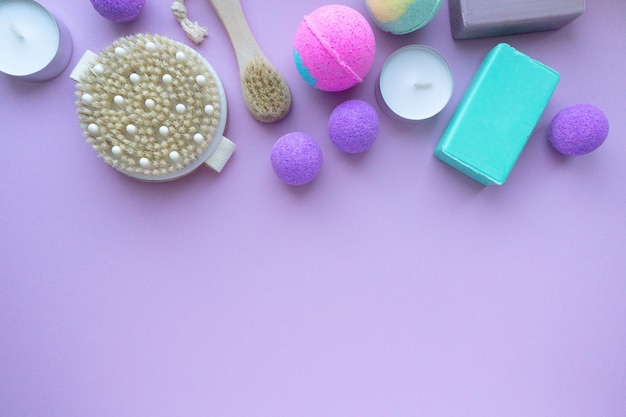 Set di prodotti termali. Bombe da bagno, sapone e spazzole per massaggi su sfondo viola, spazio per il testo