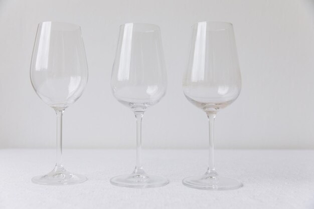 Set di ringraziamento Tre bicchieri di vino vuoti su un modello di tavolo bianco