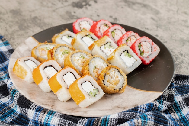 Set di rotoli di sushi freschi immessi su sfondo di pietra.