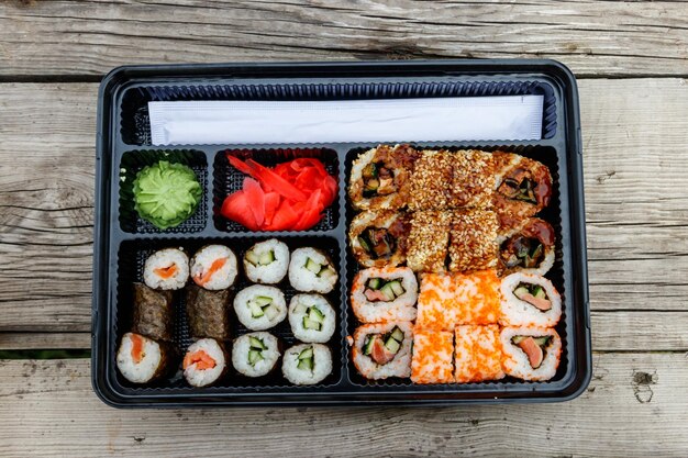Set di rotoli di sushi in scatola di plastica su tavola di legno Sushi da asporto o consegna di sushi