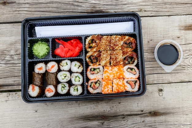 Set di rotoli di sushi in scatola di plastica su tavolo di legno Sushi da asporto o consegna di sushi in contenitore di plastica Vista dall'alto