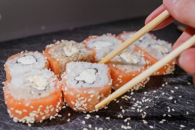 Set di rotoli di sushi serviti su tavola nera su sfondo scuro.