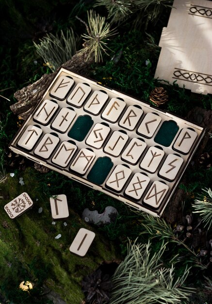 Set di rune di legno in una scatola giacciono sul muschio nella foresta. piattaforme rettangolari di legno su cui sono scolpite rune scandinave giacciono su muschio verde circondato da sale, coni, aghi di abete e corteccia