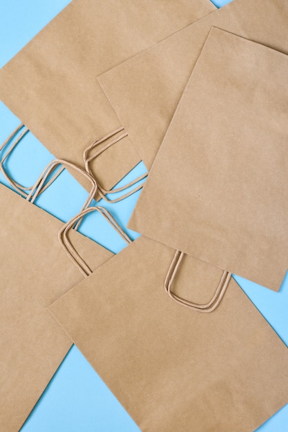 Set di sacchetti di carta artigianale per lo shopping su un tavolo blu.