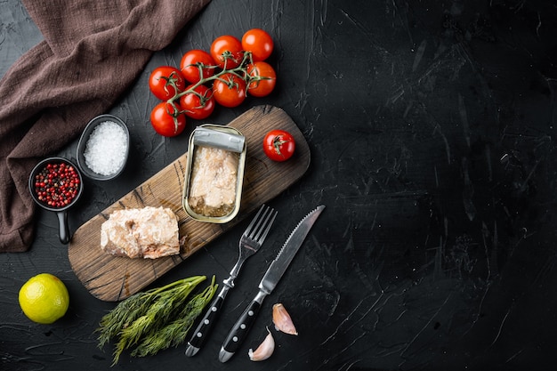 Set di salmone selvatico dell'Alaska in scatola, su tagliere di legno, su fondo nero