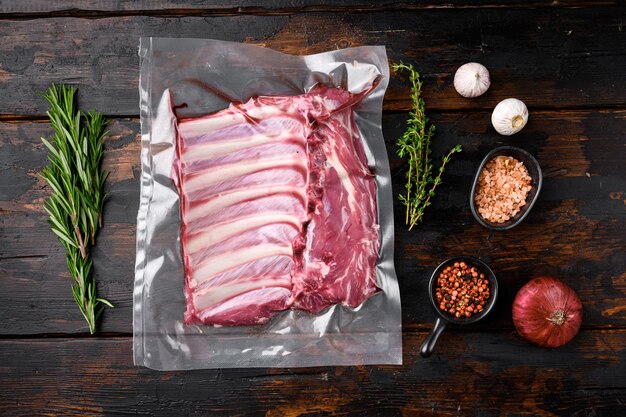 Set di scaffalature per costolette di agnello crudo confezionato per supermercato, su vecchio sfondo di tavolo in legno scuro, vista dall'alto piatta