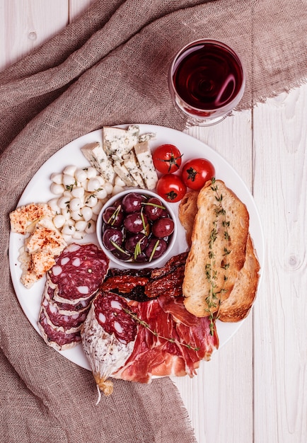 Set di snack al vino. Varietà di formaggio e carne, olive, pomodori su fondo bianco