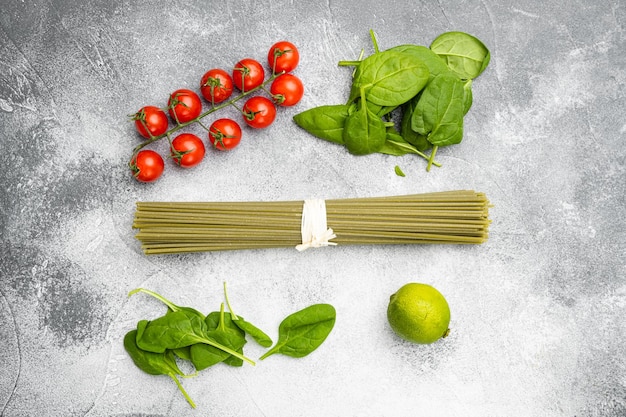 Set di spinaci secchi crudi di spaghetti di colore verde, su sfondo di tavolo in pietra grigia, vista dall'alto piatta, con spazio di copia per il testo