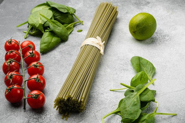 Set di spinaci secchi crudi per spaghetti di colore verde, su sfondo grigio tavolo in pietra