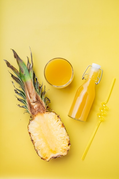 Set di succo di ananas, su sfondo estivo testurizzato giallo, vista dall'alto piatto