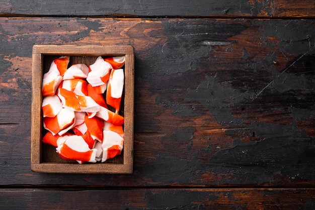 Set di surimi snack asiatico, in una scatola di legno, su sfondo di legno scuro, vista dall'alto piatto laici, con copyspace e spazio per il testo