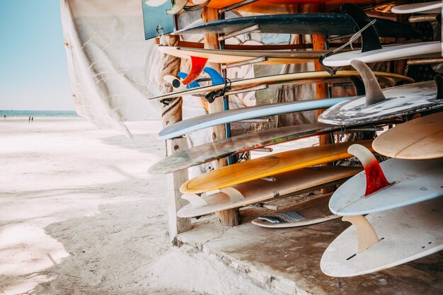 Set di tavole da surf colorati differenti in una pila disponibile per l&#39;affitto sulla spiaggia.