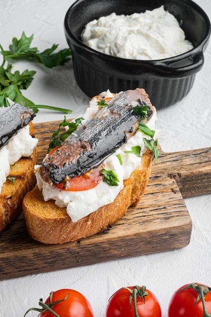 Set di toast alla ricotta e sardine, su sfondo di tavolo in pietra bianca